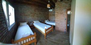 Habitación con 2 camas y pared de ladrillo en Borealis Guest House en Koman
