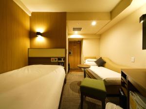 a hotel room with two beds and a table at Super Hotel Lohas Ikebukuro-Eki Kitaguchi in Tokyo