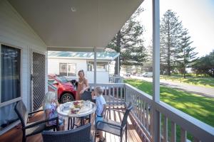 a woman and two children standing on a porch at Werri Beach Holiday Park in Gerringong