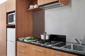 a kitchen with a stove with a pot on it at Punthill Apartment Hotel - Little Bourke in Melbourne