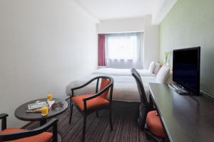 a hotel room with a bed and a table and chairs at the b hakata in Fukuoka