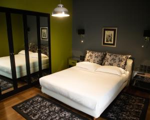 a bedroom with a white bed and a mirror at Andromeda Suites in Athens