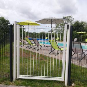 un portail avec des chaises et des parasols à côté d'une piscine dans l'établissement Gîte le Pech, à Sainte-Foy-de-Longas