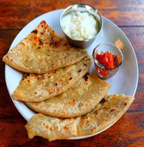 een witte plaat met vijf tortilla's en een kom saus bij Hotel rr palace in Ahmedabad