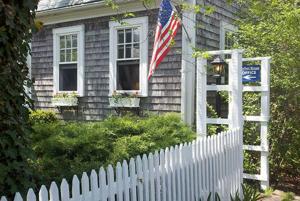 una recinzione bianca di fronte a una casa con una bandiera di Moffett House Inn a Provincetown