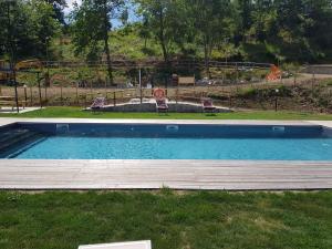 una piscina con due sedie e un parco giochi di Agriturismo Podere Omomorto a Pratovecchio