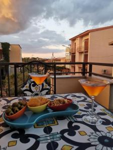 uma mesa com dois cocktails e tigelas de comida numa varanda em App.Violet Sardegna Mare La Caletta em La Caletta