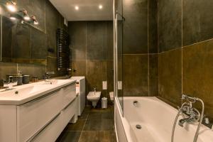 a bathroom with two sinks and a tub and a toilet at Galeria Italiana Apartments in Wrocław