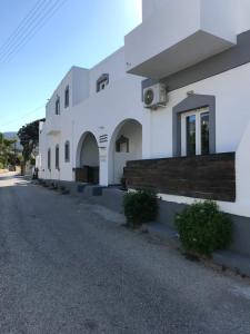 a white building with a street in front of it at Ammos Luxury Studios in Aliki