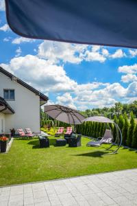 Blick auf einen Garten mit Stühlen und einem Sonnenschirm in der Unterkunft Rajska Oaza in Przybradz