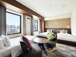 ein Hotelzimmer mit 2 Betten und einem Tisch in der Unterkunft Hotel Elcient Osaka Umeda in Osaka
