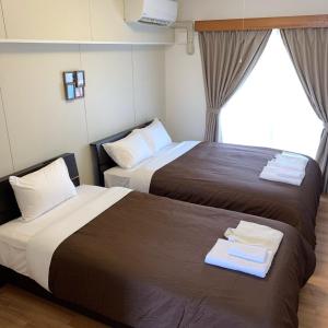 a hotel room with two beds and a window at Y' RISE TO HOTEL Miyakojima in Miyako Island