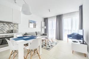 a white kitchen and living room with a table and chairs at Marina Royale Darłowo - Apartamenty Ultra Mar nad morzem in Darlowko