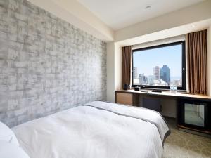 a bedroom with a white bed and a window at Hotel Elcient Osaka in Osaka