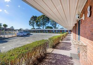 op een stoep naast een parkeerplaats bij Burwood East Motel in Burwood