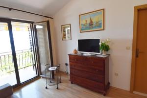 a living room with a television on a wooden dresser at Villa DELFINA in Podgora