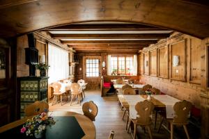 a restaurant with wooden tables and chairs and windows at Raselli Sport Hotel in Le Prese, Poschiavo