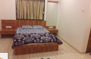 a bedroom with a bed with a brown comforter at Gold Nest Valley View 3BHK (3DAYS MINI. STAY) in Panchgani