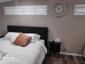 1 dormitorio con 1 cama con reloj en la pared en La Nest Private Studio en Gorokan