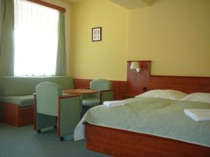 ein Hotelzimmer mit einem Bett, Stühlen und einem Fenster in der Unterkunft Hotel Praha in Deštné v Orlických horách