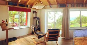 1 dormitorio con 1 cama, escritorio y 2 ventanas en Quinta dos Artistas en Santa Cruz