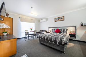 a bedroom with a bed and a table and chairs at Shearing Shed Motor Inn in Dubbo