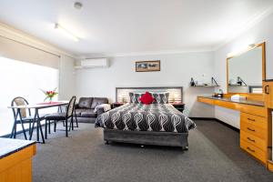 a bedroom with a bed and a living room at Shearing Shed Motor Inn in Dubbo