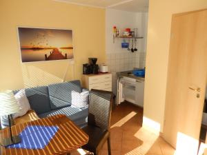 ein Wohnzimmer mit einem blauen Sofa und einer Küche in der Unterkunft Bungalow (hälfte) Steuerbord Ahlbeck (Usedom) in Ahlbeck