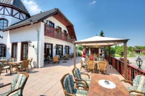 eine Terrasse mit Tischen, Stühlen und einem Sonnenschirm in der Unterkunft Hotel Freihof in Hiddenhausen