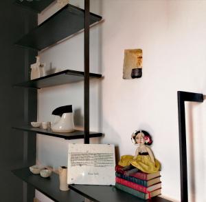 ein Regal mit einer Puppe, die auf einem Stapel Bücher sitzt in der Unterkunft CASAVERO in Oroklini