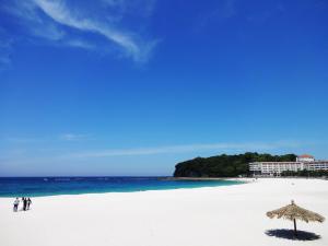 eine Gruppe von Menschen, die mit einem Sonnenschirm am Strand spazieren in der Unterkunft Minshuku Inn Shirahama Uminoyado in Shirahama