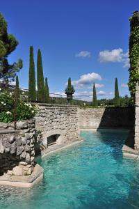 a pool of water with a stone wall and trees at La Bastide de Marie, Maisons et Hôtels Sibuet in Ménerbes