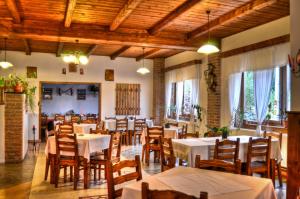 un restaurante con mesas blancas y sillas de madera en Csíki Határ Fogadó/ Hanul Hotarul Ciucului en Bixad