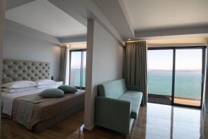 a bedroom with a bed and a chair and a large window at Aianteion Bay Luxury Hotel & Suites in Aiándion