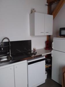 a kitchen with white cabinets and a sink and a refrigerator at ROMANN 2 in Xonrupt-Longemer