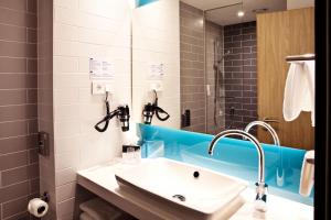 ein Badezimmer mit einem weißen Waschbecken und einer Dusche in der Unterkunft Holiday Inn Express Frankfurt Airport - Raunheim, an IHG Hotel in Raunheim