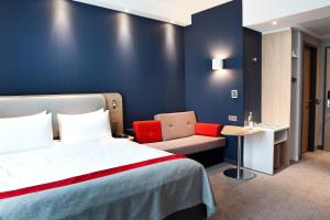 ein Hotelzimmer mit einem Bett und einem Stuhl in der Unterkunft Holiday Inn Express Frankfurt Airport - Raunheim, an IHG Hotel in Raunheim