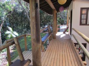 eine Holzveranda mit Bänken an einem Haus in der Unterkunft Nalua Guest House in Guarda do Embaú