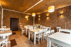 a restaurant with white tables and chairs and a brick wall at Eko Hotel Na Wierzynka & Park Pinokia in Wieliczka