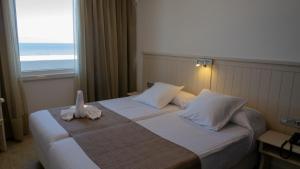 a hotel room with a bed with towels on it at Apartamentos Turisticos Flamero in Matalascañas +6 photos