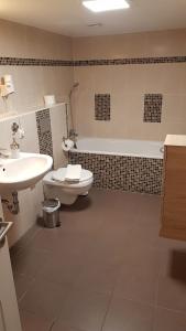a bathroom with a toilet and a sink and a tub at Landhotel Klempau in Lübeck +49 photos
