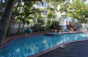 a large swimming pool with palm trees and a building at Surfers Del Rey in Gold Coast