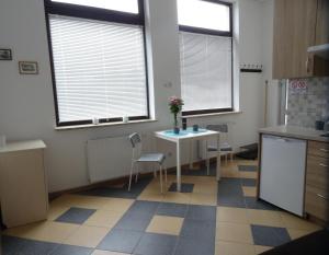 a kitchen with a table and chairs and two windows at Nowy Apartament Słoneczny in Augustów