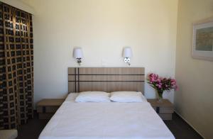 a bedroom with a bed with white sheets and flowers at Panorama Hotel in Agia Marina Aegina