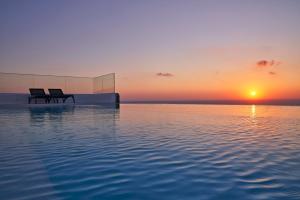two chairs sitting on a pool of water at sunset at Villa Rodakes in Vourvoulos
