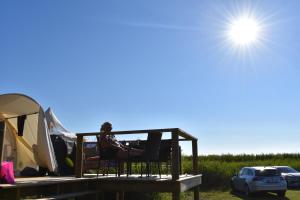 Føllenslev的住宿－Vesterlyng Camping and Cottages，坐在帐篷前椅子上的女人