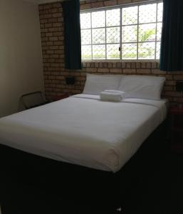a large white bed in a bedroom with a window at Caboolture Motel in Caboolture