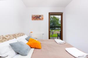 a bedroom with a bed with orange and gray pillows at Apartament nad Zatoką Pucką in Puck