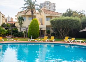 uma piscina com espreguiçadeiras e um edifício em Aparthotel Villas La Manga em La Manga del Mar Menor