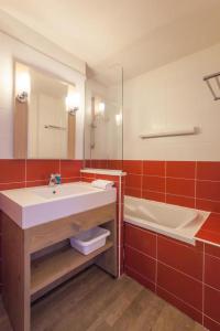 ein Badezimmer mit einem Waschbecken, einer Badewanne und einem Spiegel in der Unterkunft Résidence Les Gémeaux - Belle Plagne in La Plagne